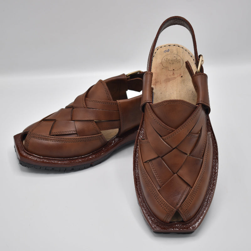 Pair of brown leather sandals on a light gray background